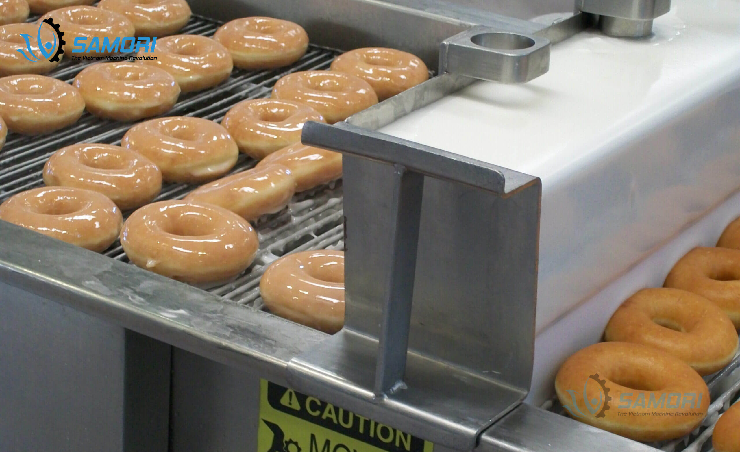 Bánh donut trong công đoạn di chuyển bằng băng tải lưới inox Bánh donut trong công đoạn di chuyển bằng băng tải lưới inox